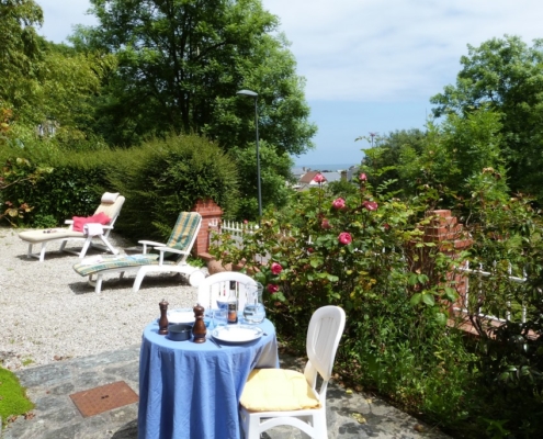 La terrasse du gite l'avenue avec la table du déjeuner, vue sur le mer de la manche et les bains de soleil